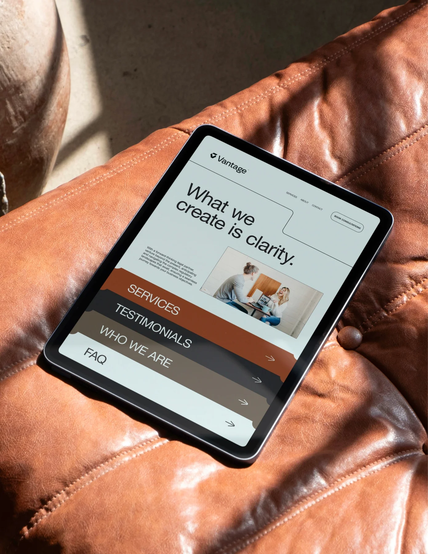 Vantage website displayed on a tablet resting on a leather chair.