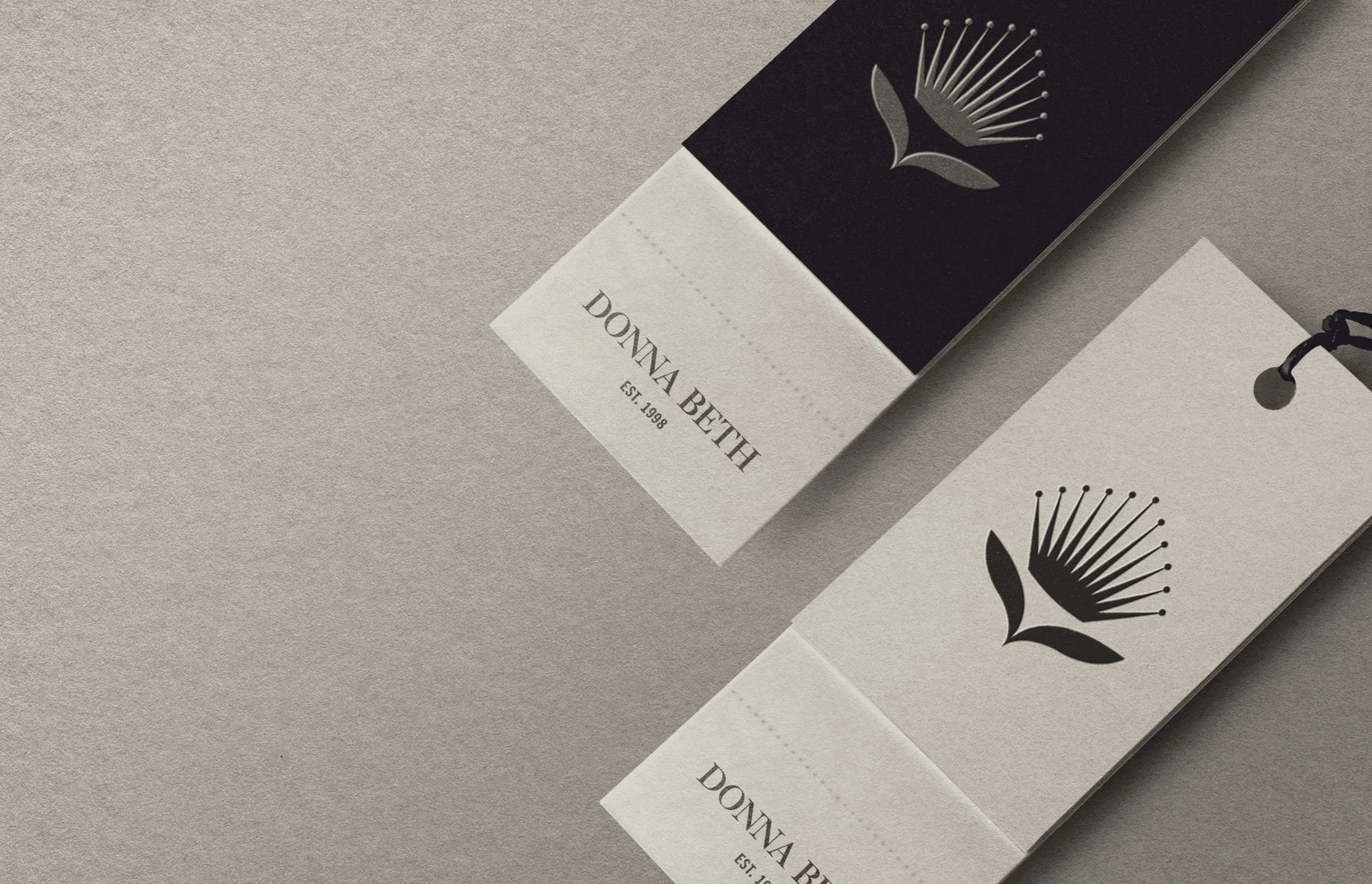 Donna Beth garment tags with a botanical emblem and contrasting cream and black panels.