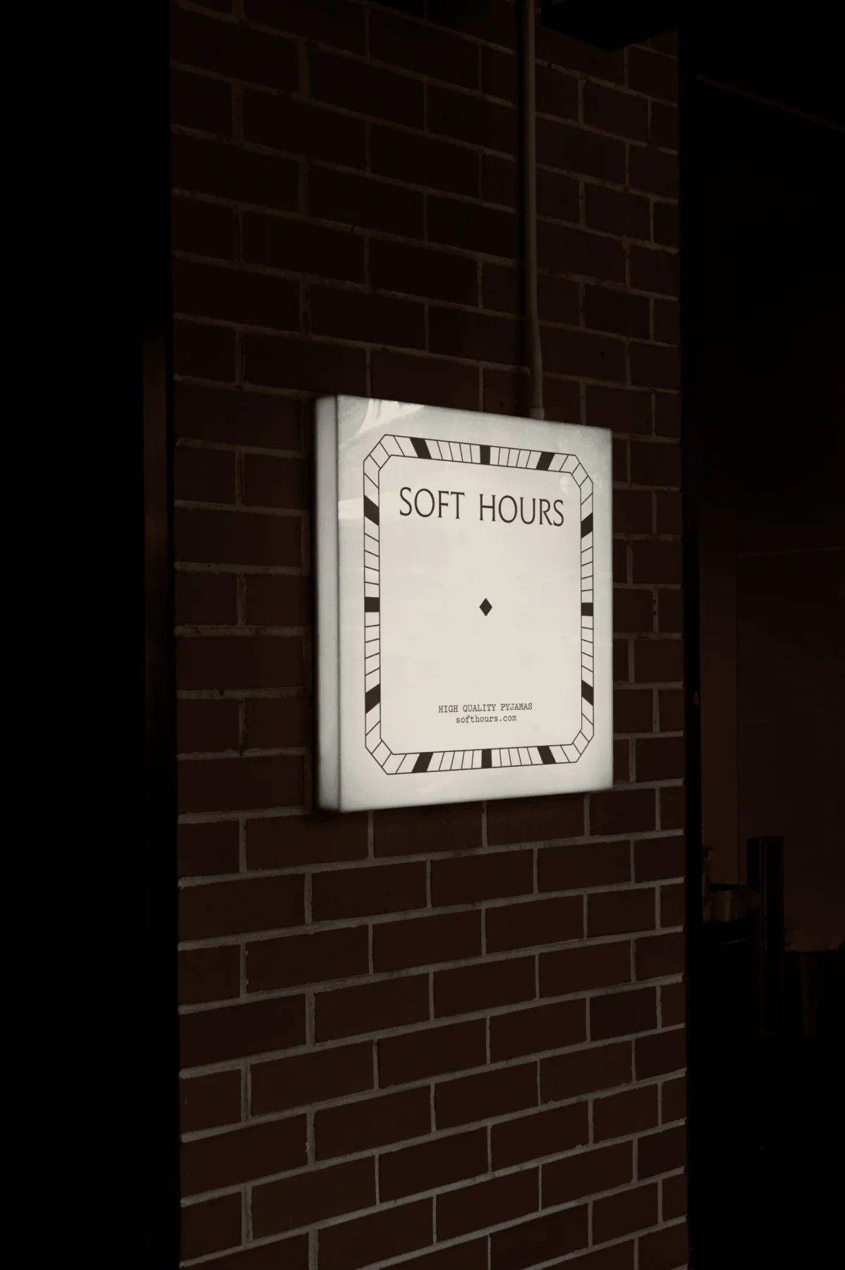 Soft Hours poster mounted on a dark brick wall.
