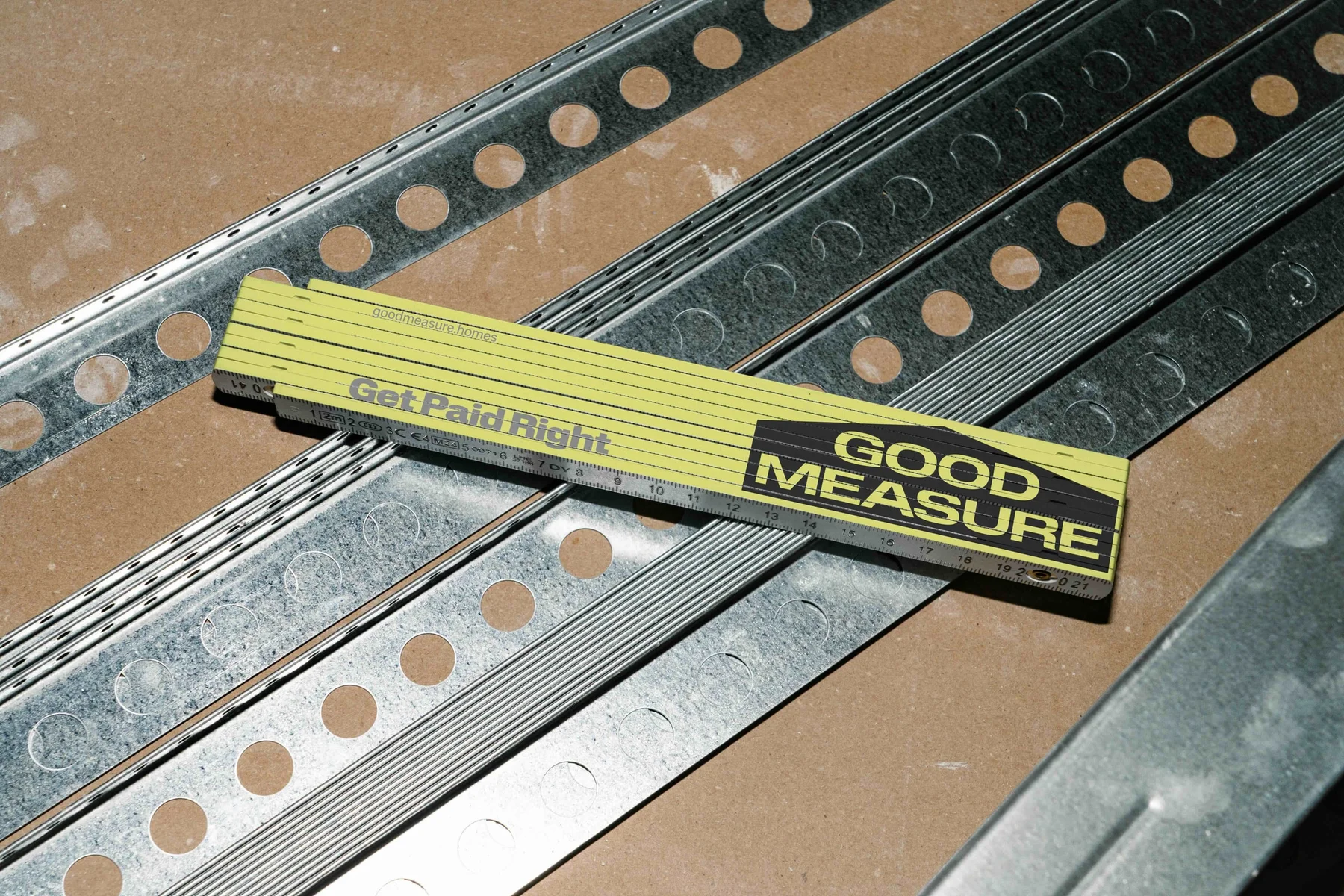 Yellow Good Measure measuring rule resting on metal framing.