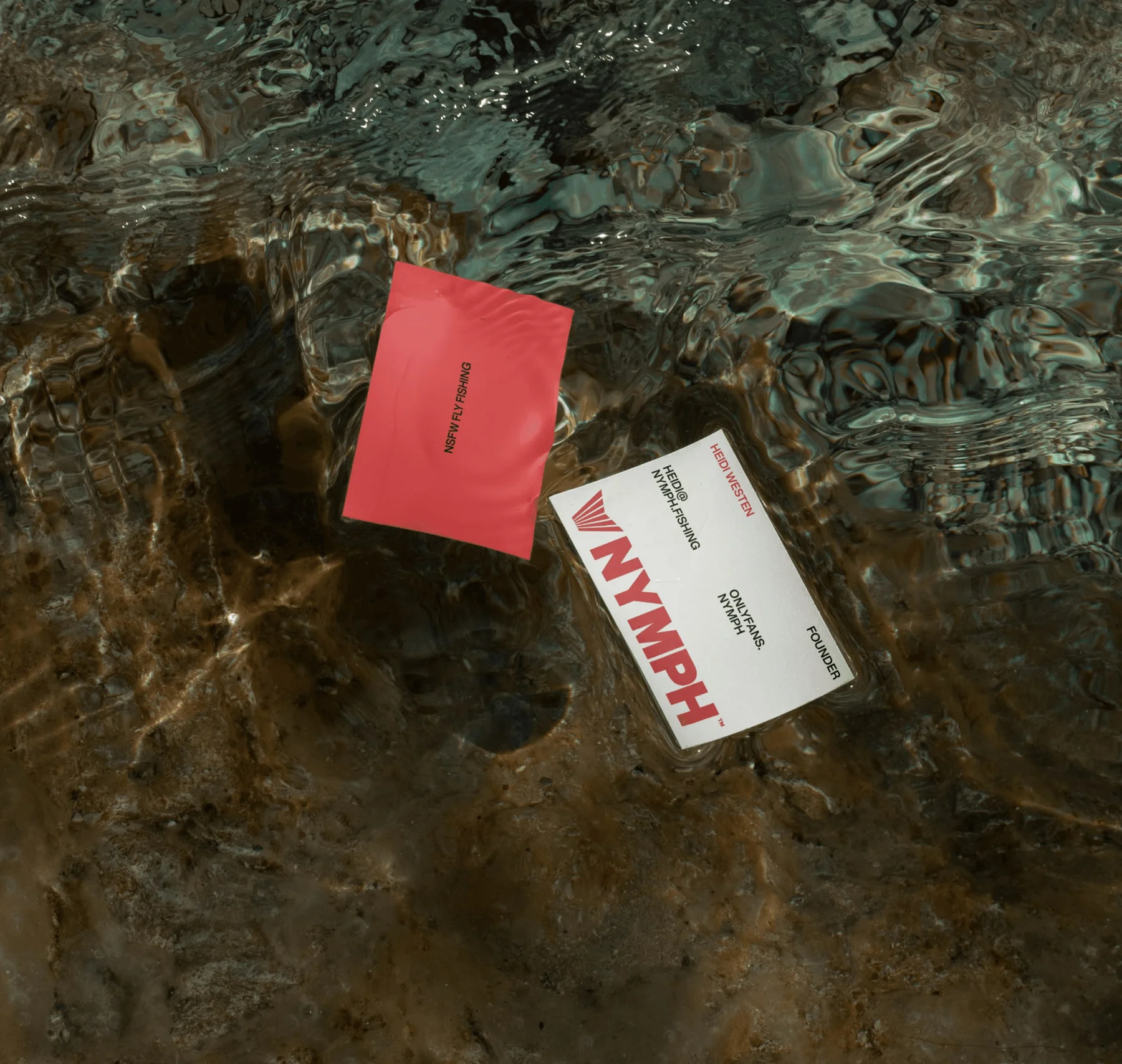Red and white Nymph cards lying in shallow water.