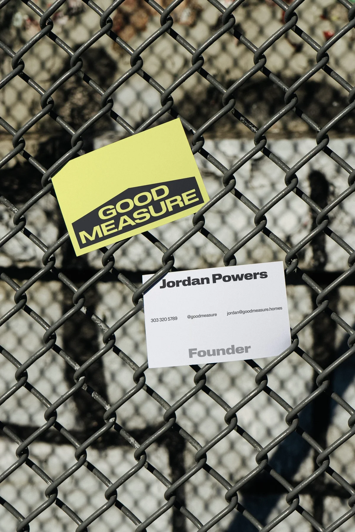 Good Measure business cards attached to a chain-link fence.