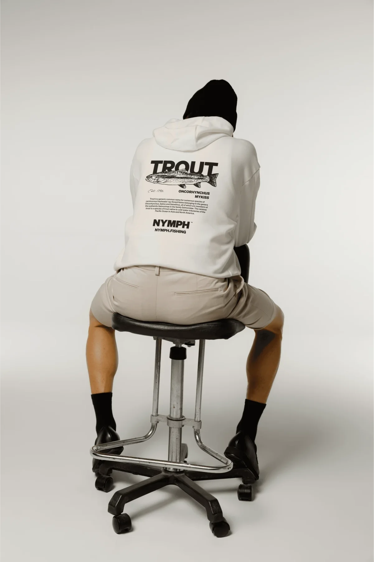 Person seated wearing a cream graphic Nymph hoodie.