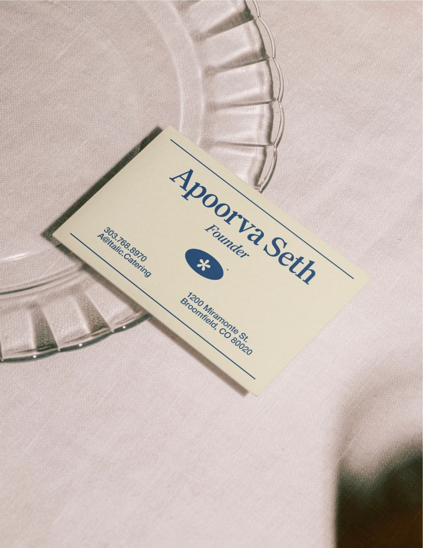 Cream Italic business card on a clear plate.