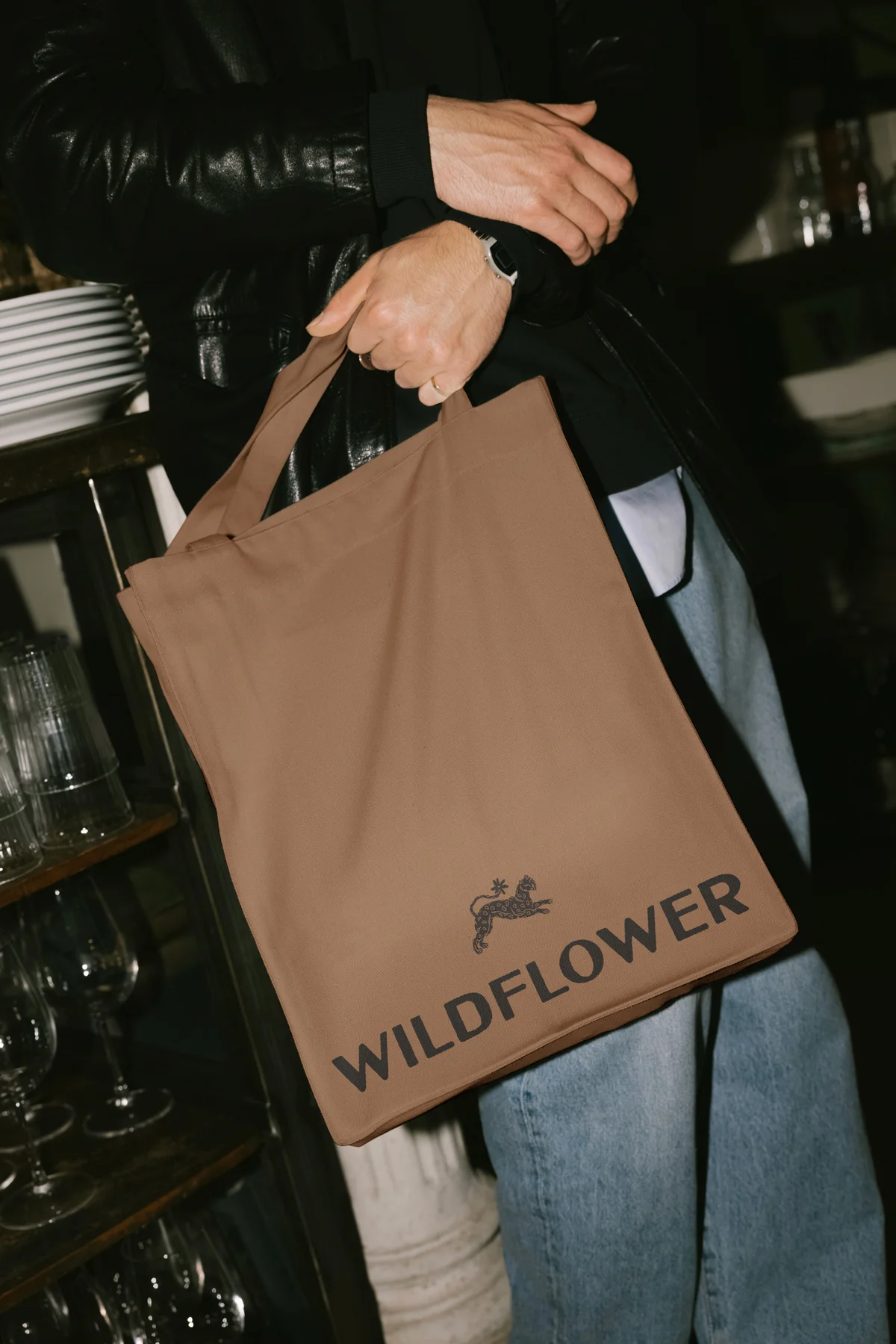Person carrying a brown Wildflower shopping bag.