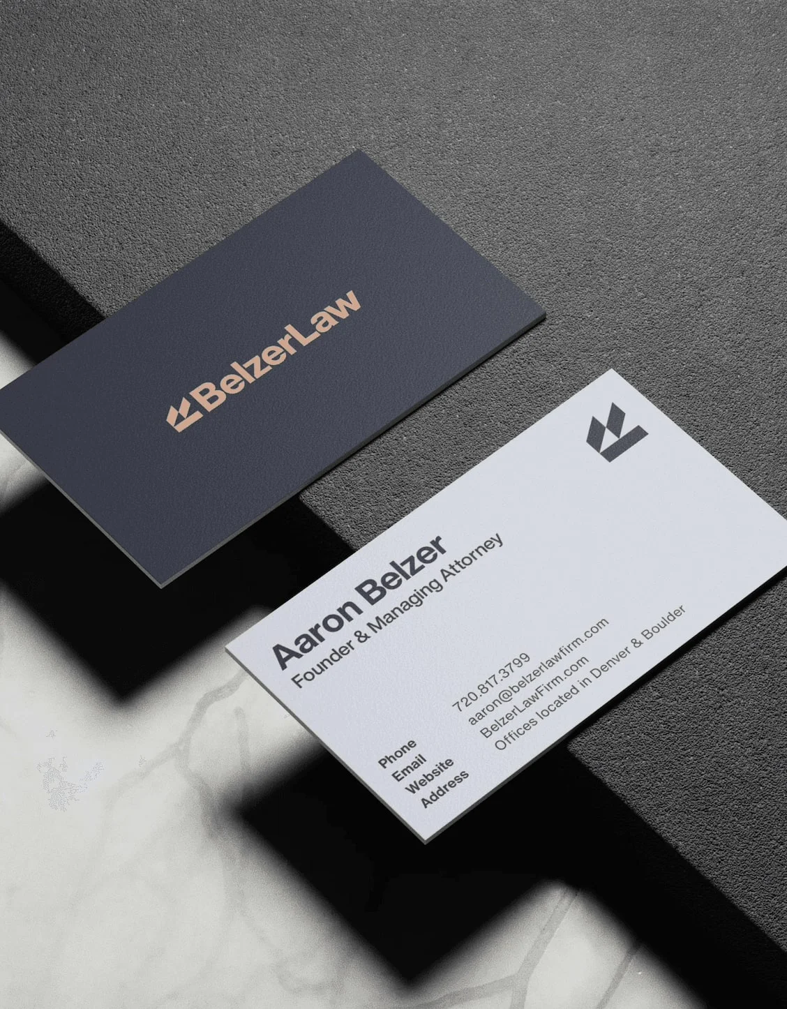 Dark and white Belzer Law business cards on concrete.