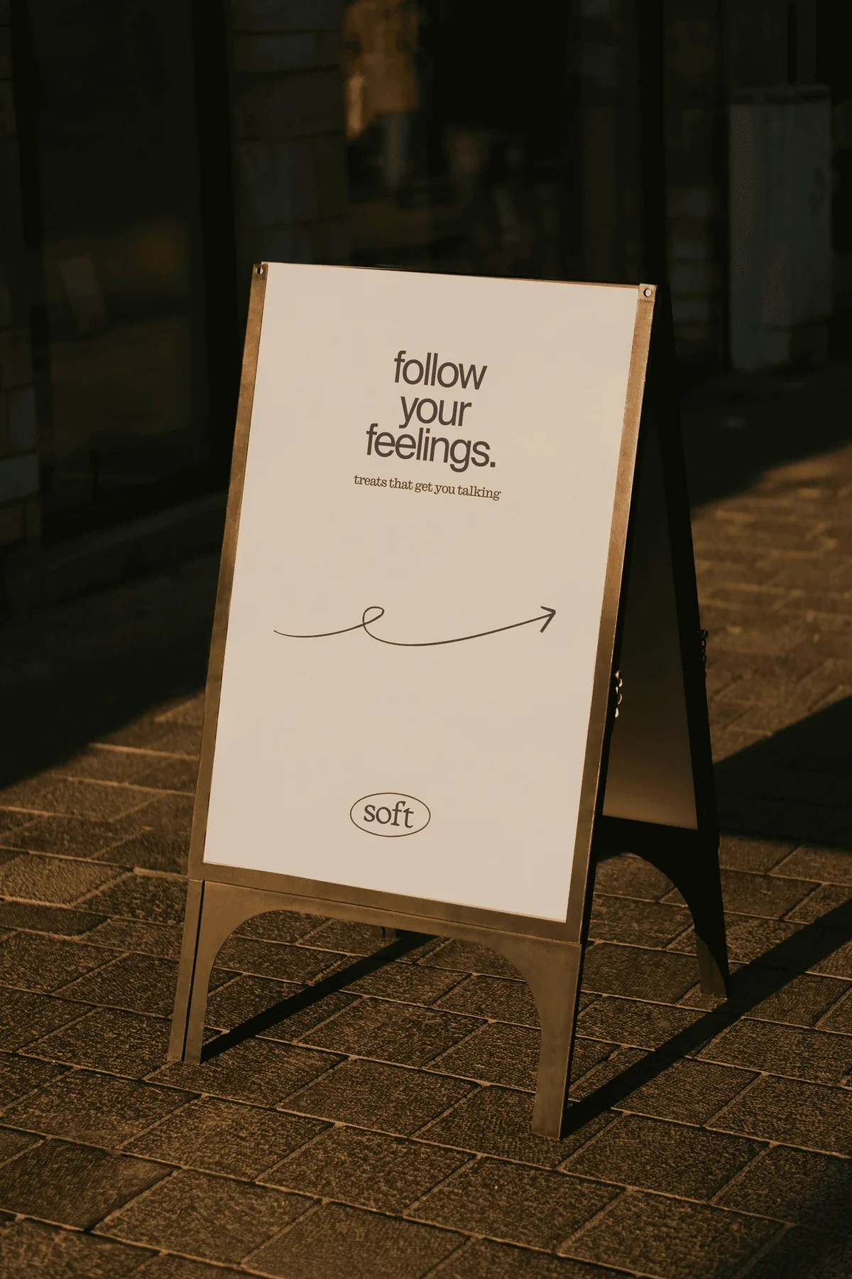 Soft sidewalk sign reading follow your feelings.