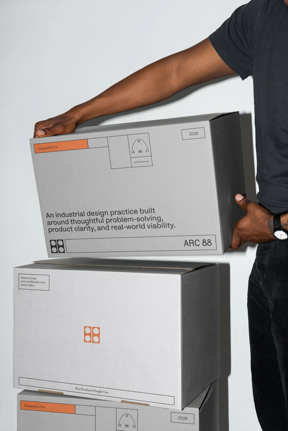 Person holding white Arc 88 product boxes with orange and black graphics.