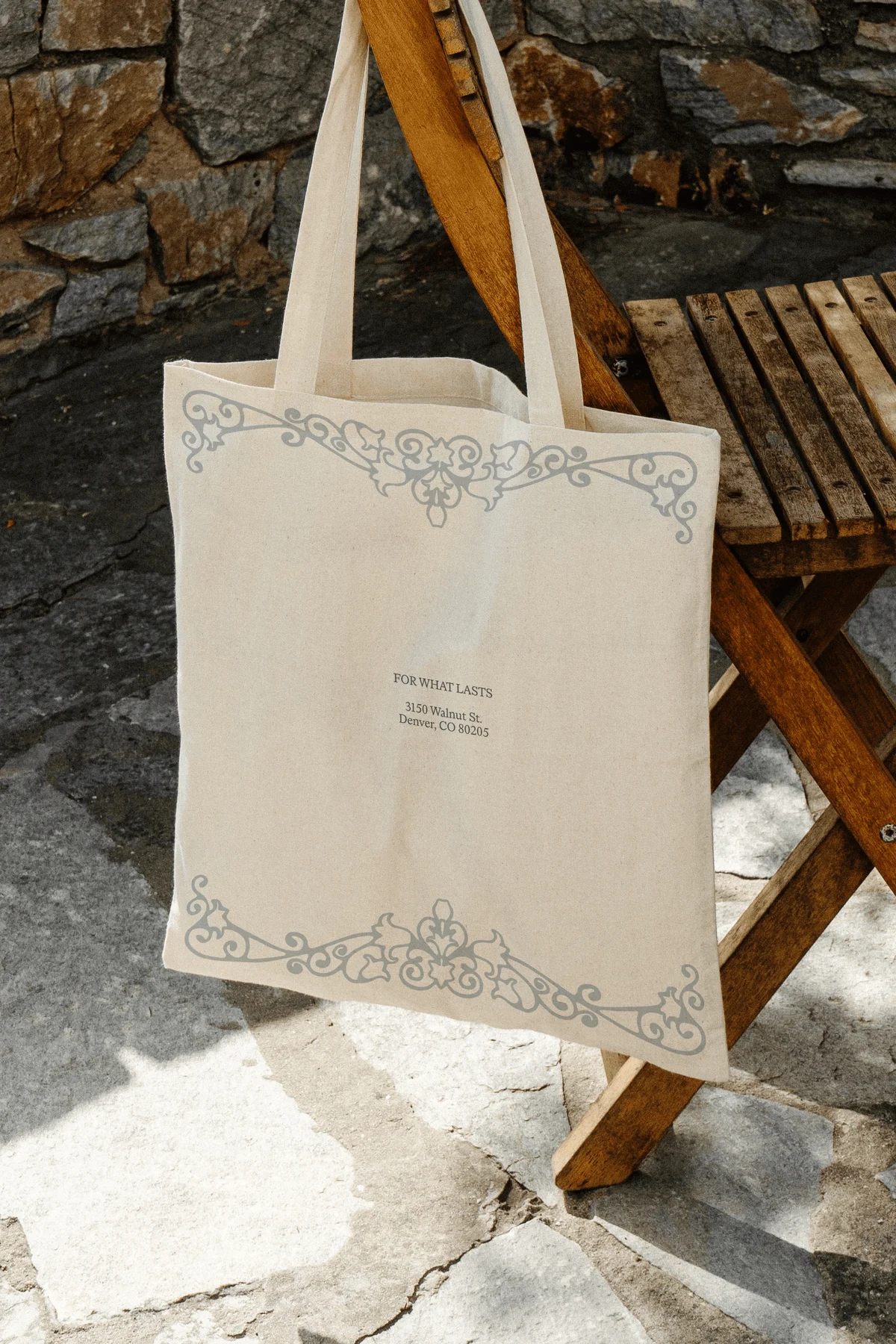 Cream tote bag with an ornamental border hanging from a chair.