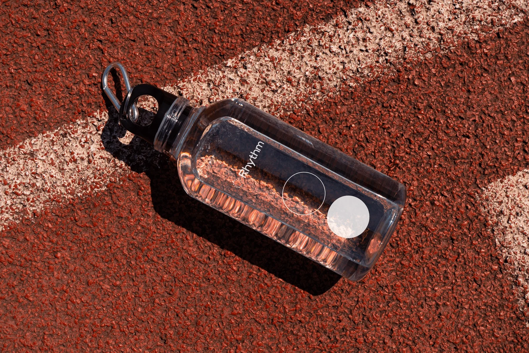 Clear Rhythm water bottle on a running track.