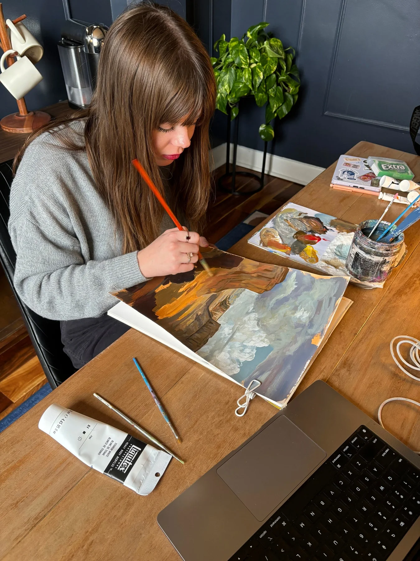 Artist painting the desert landscape at a worktable.