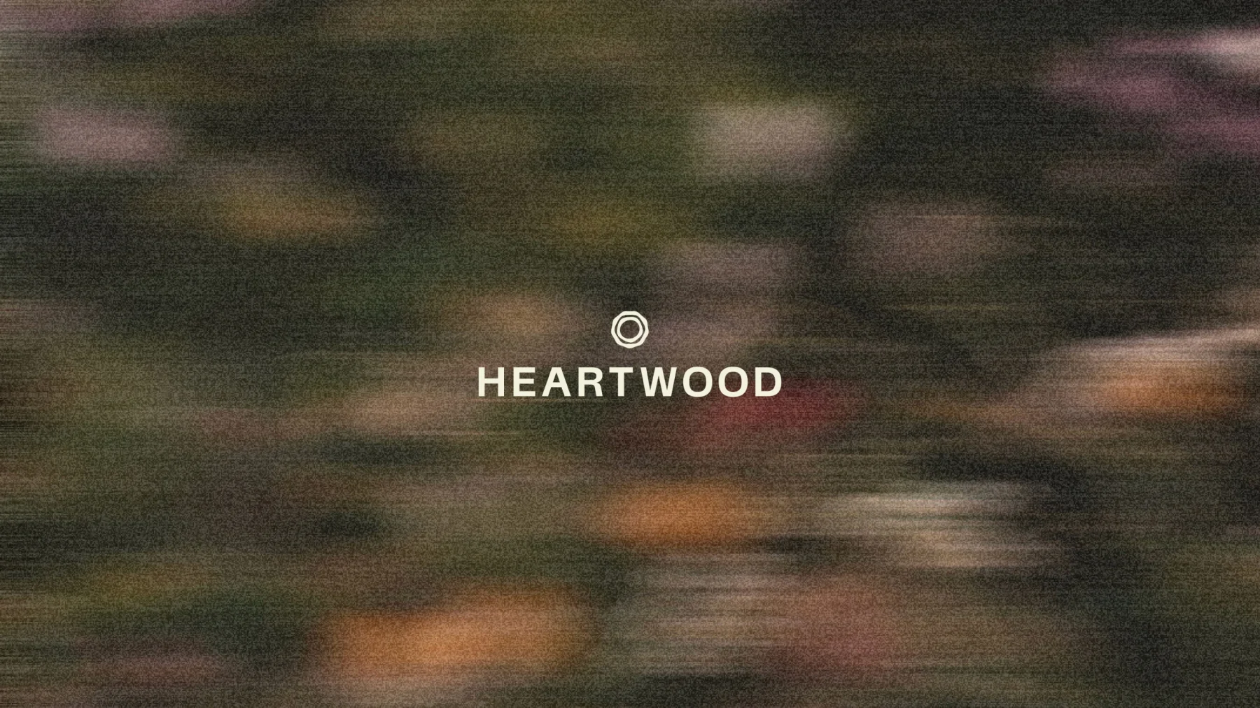 Small white Heartwood wordmark over blurred woodland photography.