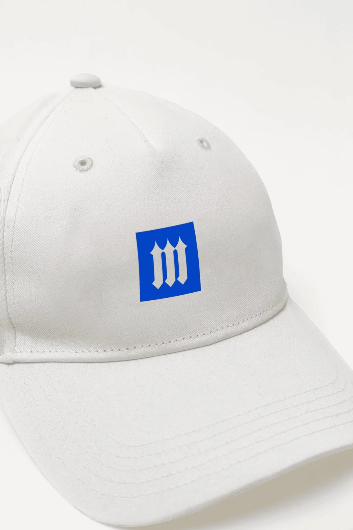White cap with a blue Moat monogram patch.