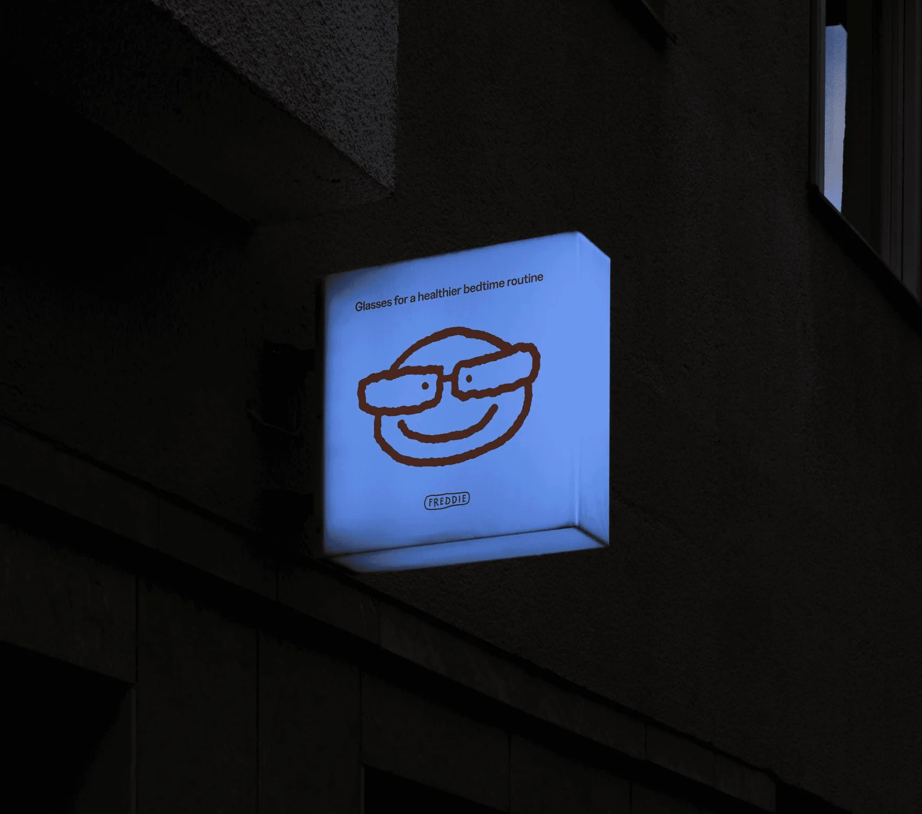 Illuminated Freddie sign with a smiling glasses illustration.