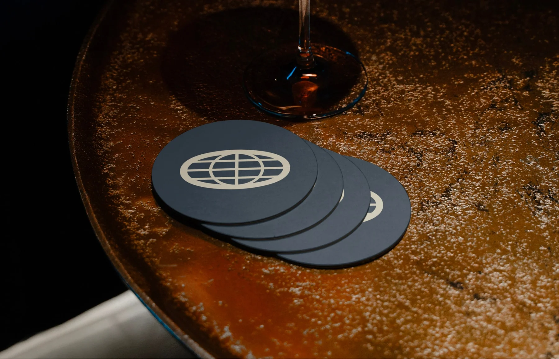 Dark blue-gray coasters with The Passenger globe emblem.