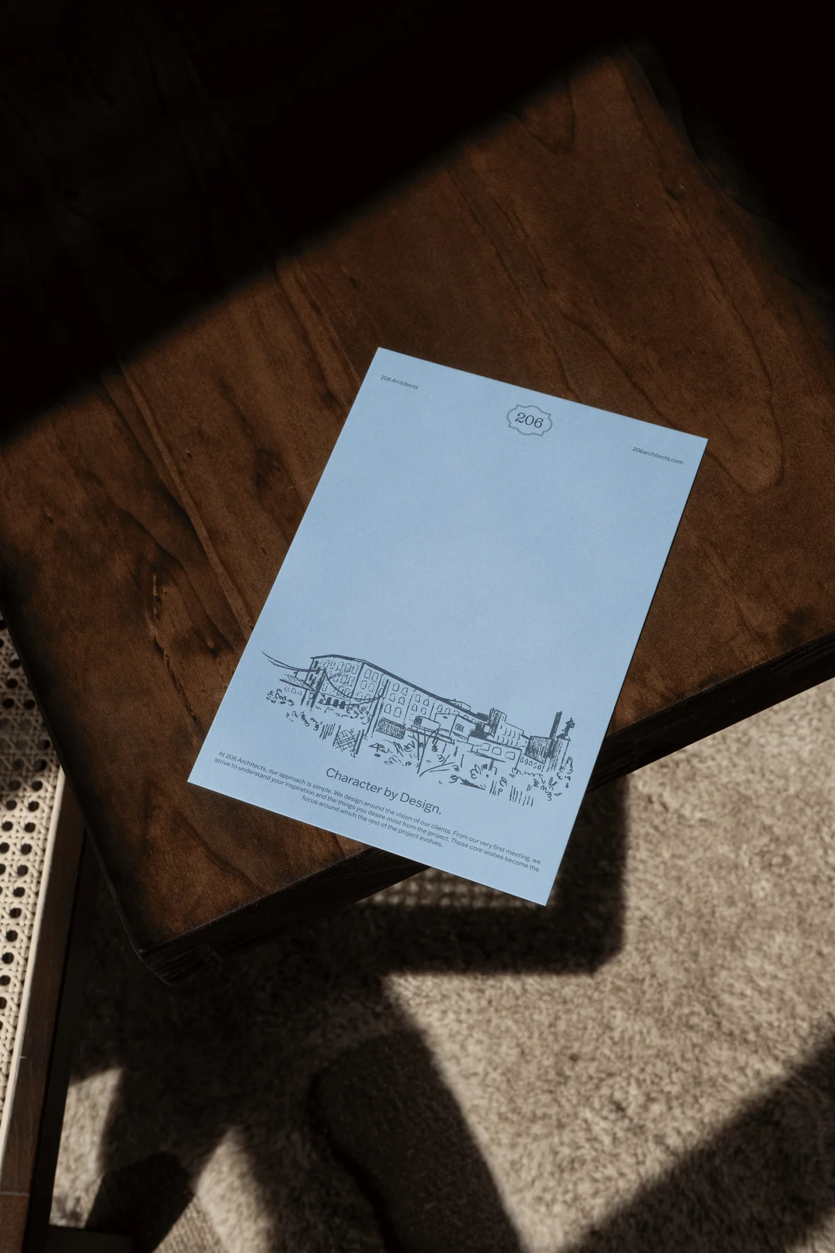 Pale blue printed brochure on a sunlit wooden surface.