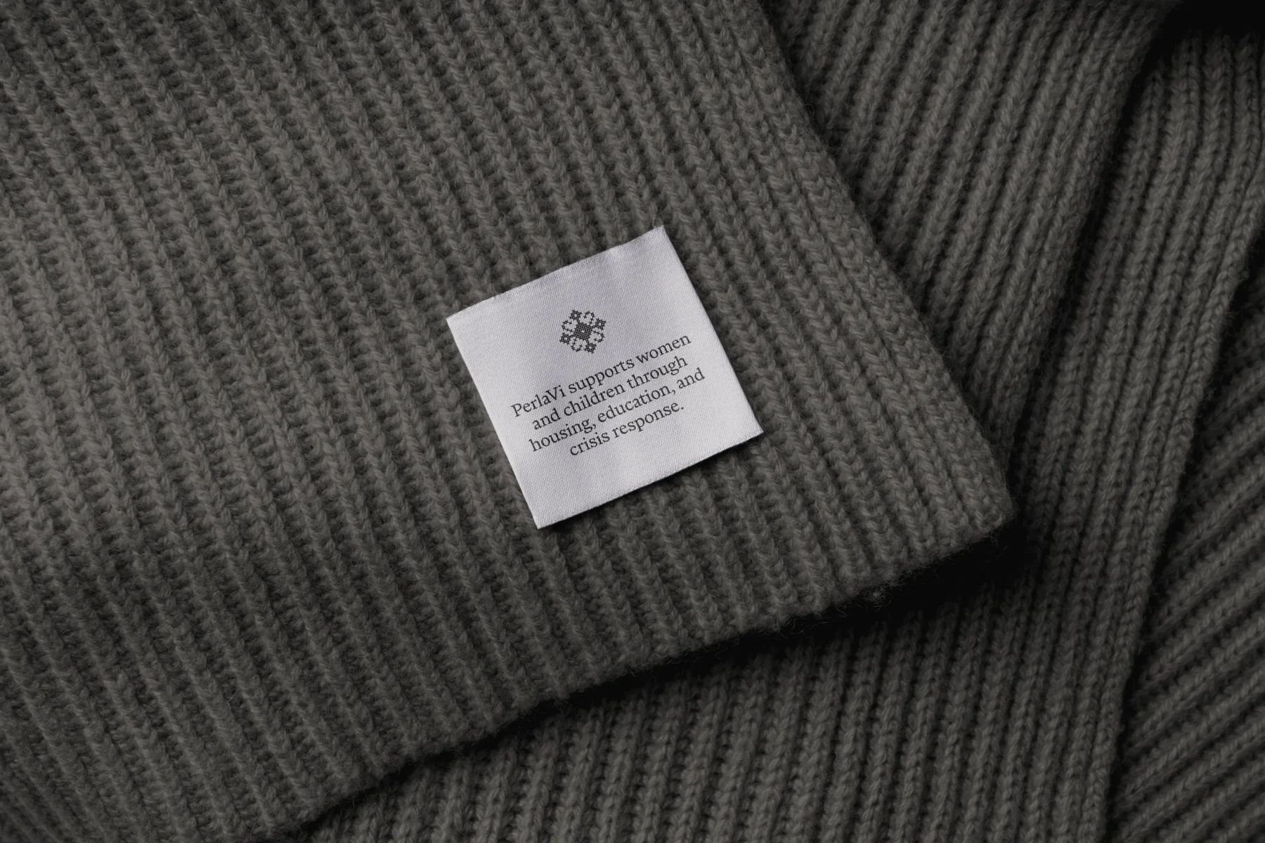 PerlaVi clothing label sewn onto dark knit fabric.