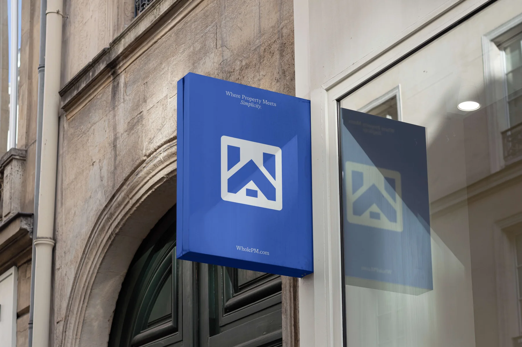 Blue Whole projecting sign with a geometric house emblem.