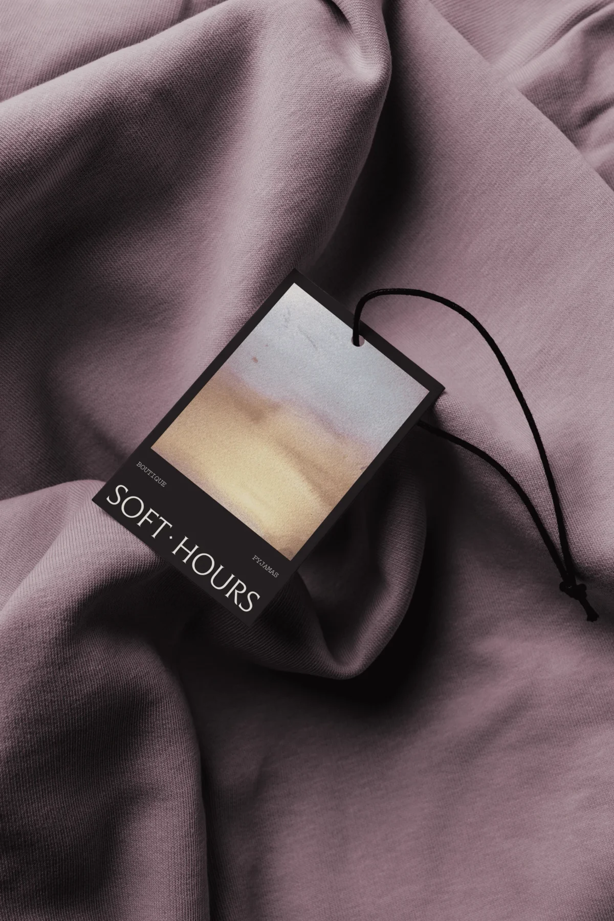 Soft Hours illustrated clothing tag on mauve fabric.