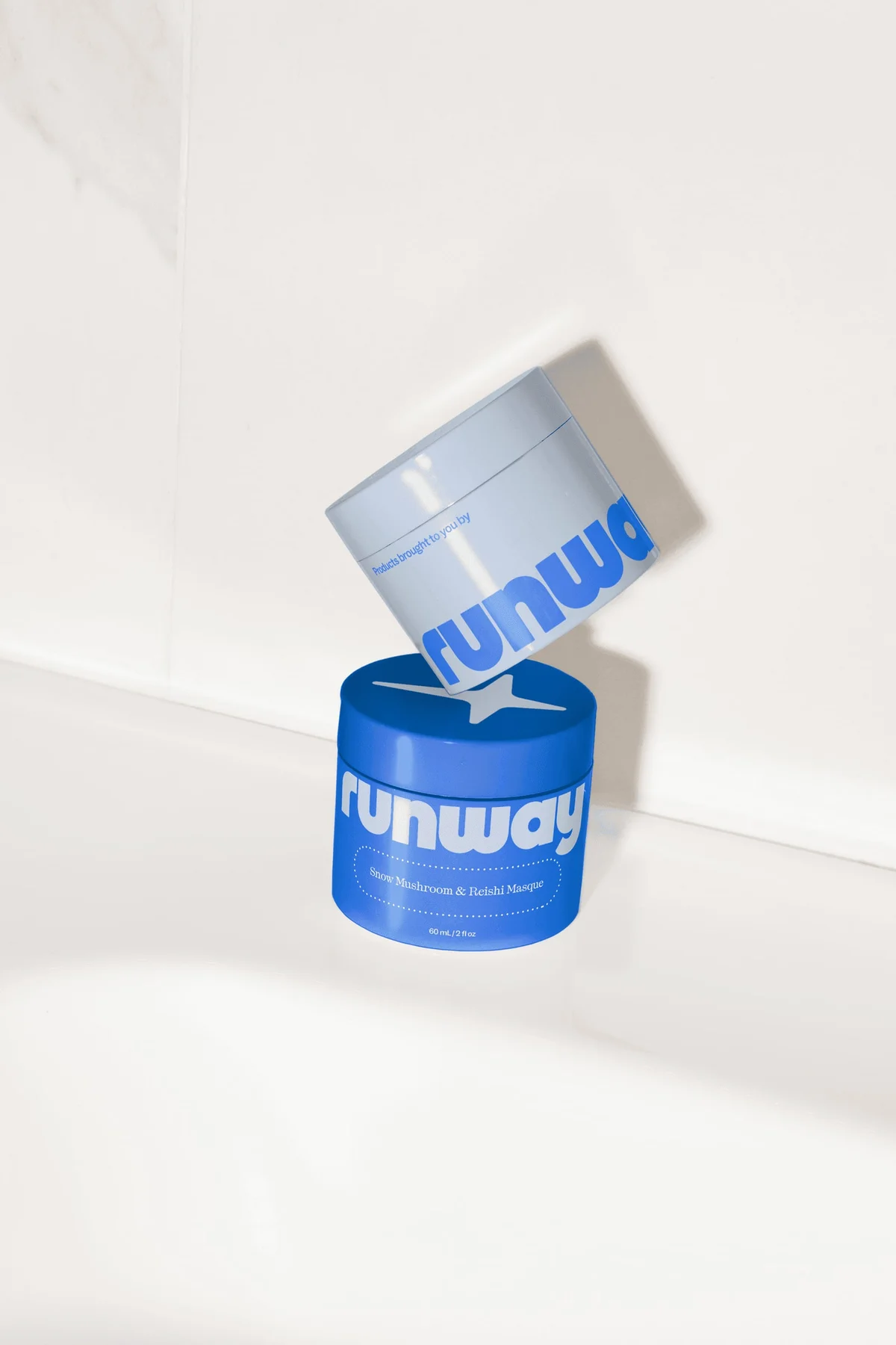 Two Runway product jars with blue and silver labels.