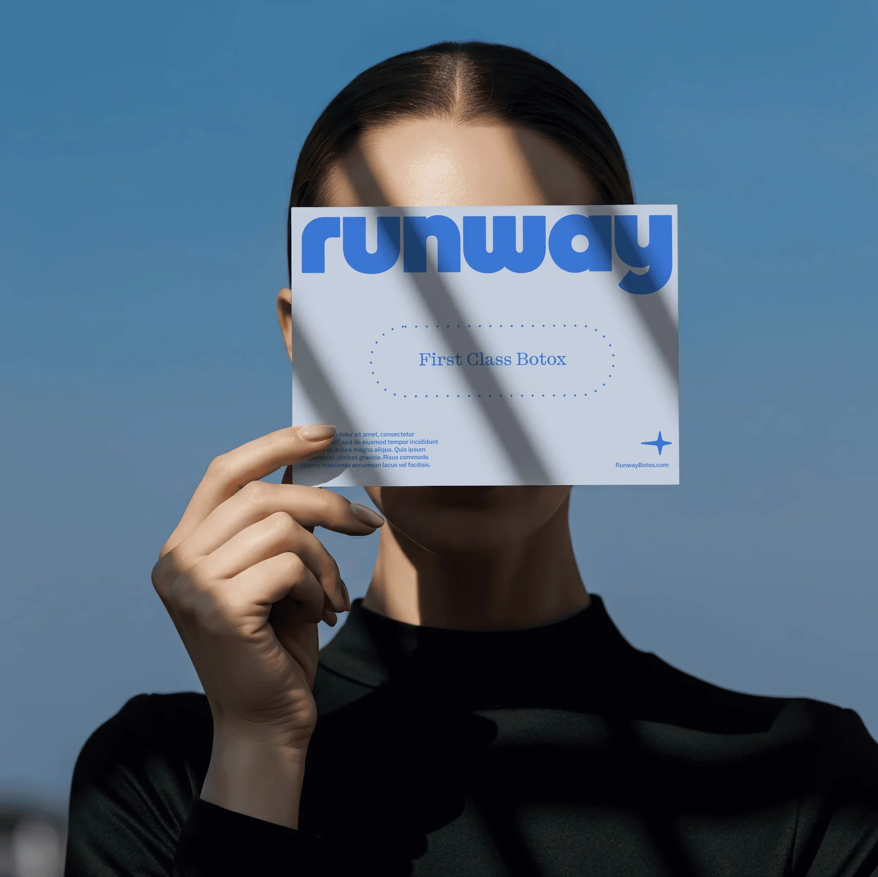 Person holding a pale blue Runway publication in front of their face.