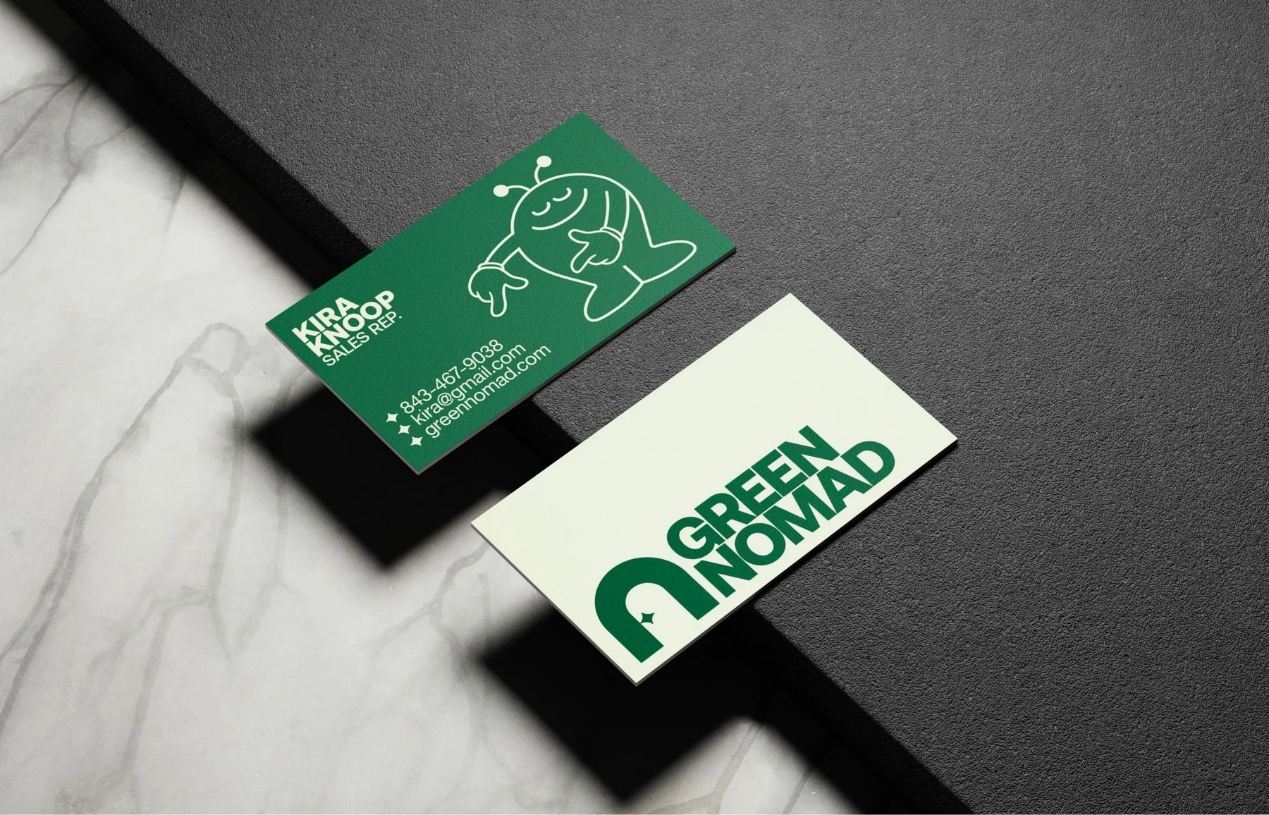 Green and cream Green Nomad business cards with an illustrated character.