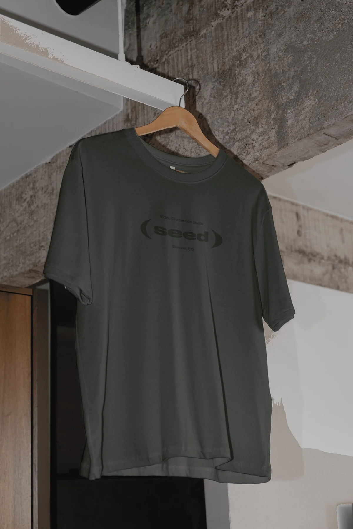 Dark gray Seed T-shirt hanging from a wooden hanger.