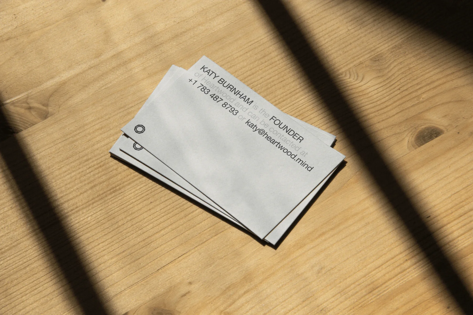 White Heartwood business cards on a sunlit wooden table.