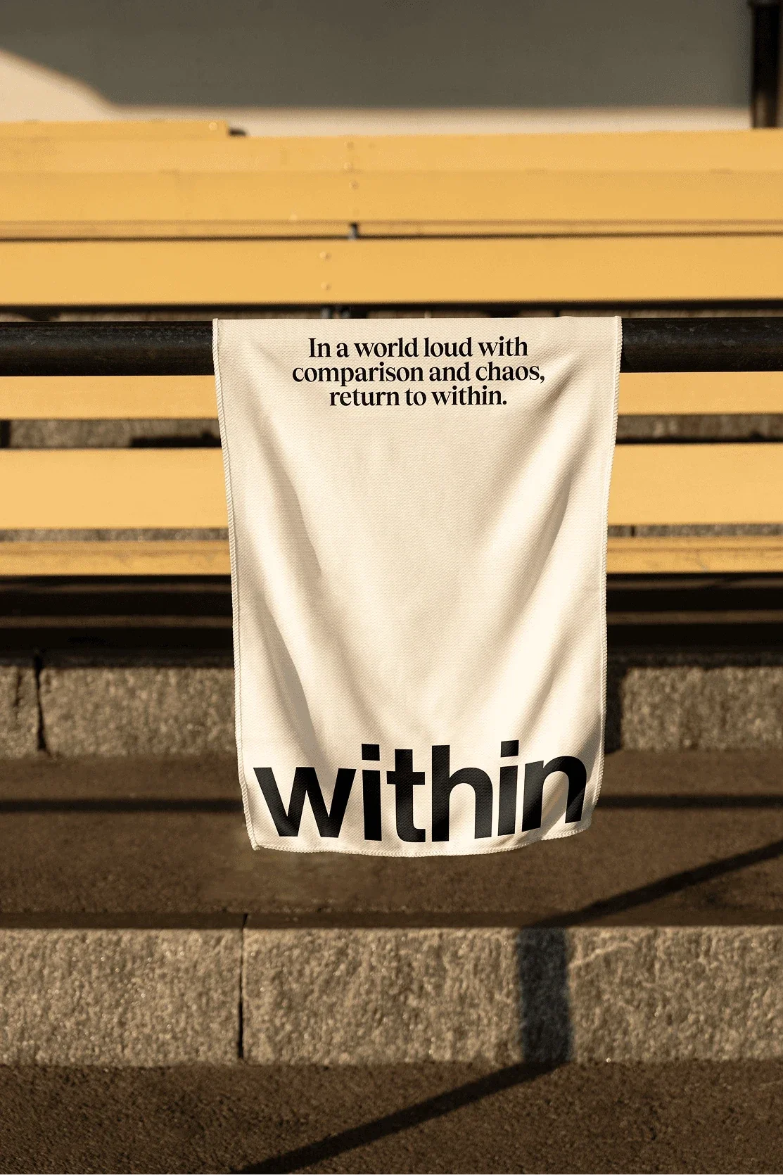 Cream Within towel draped over a yellow bench.