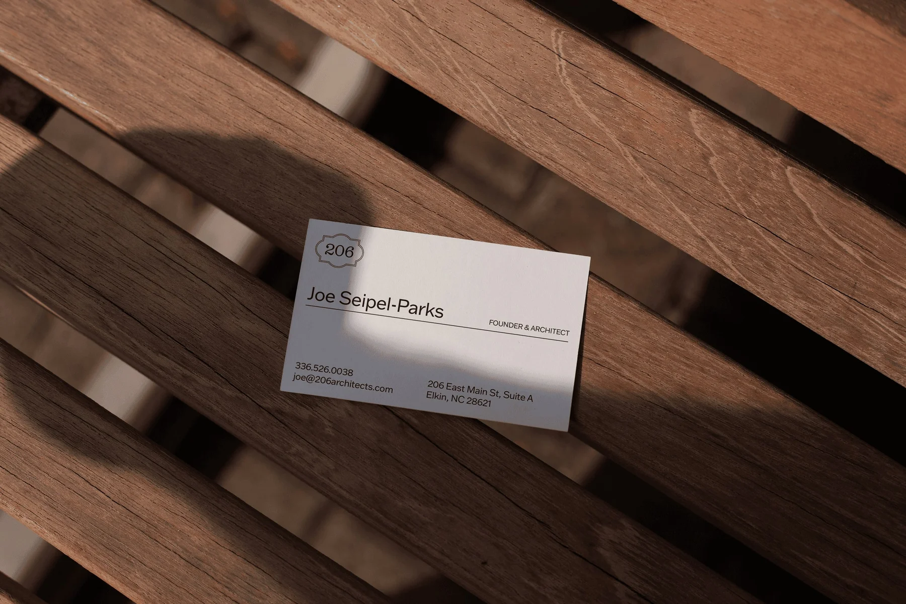 White 206 business card on wooden slats.