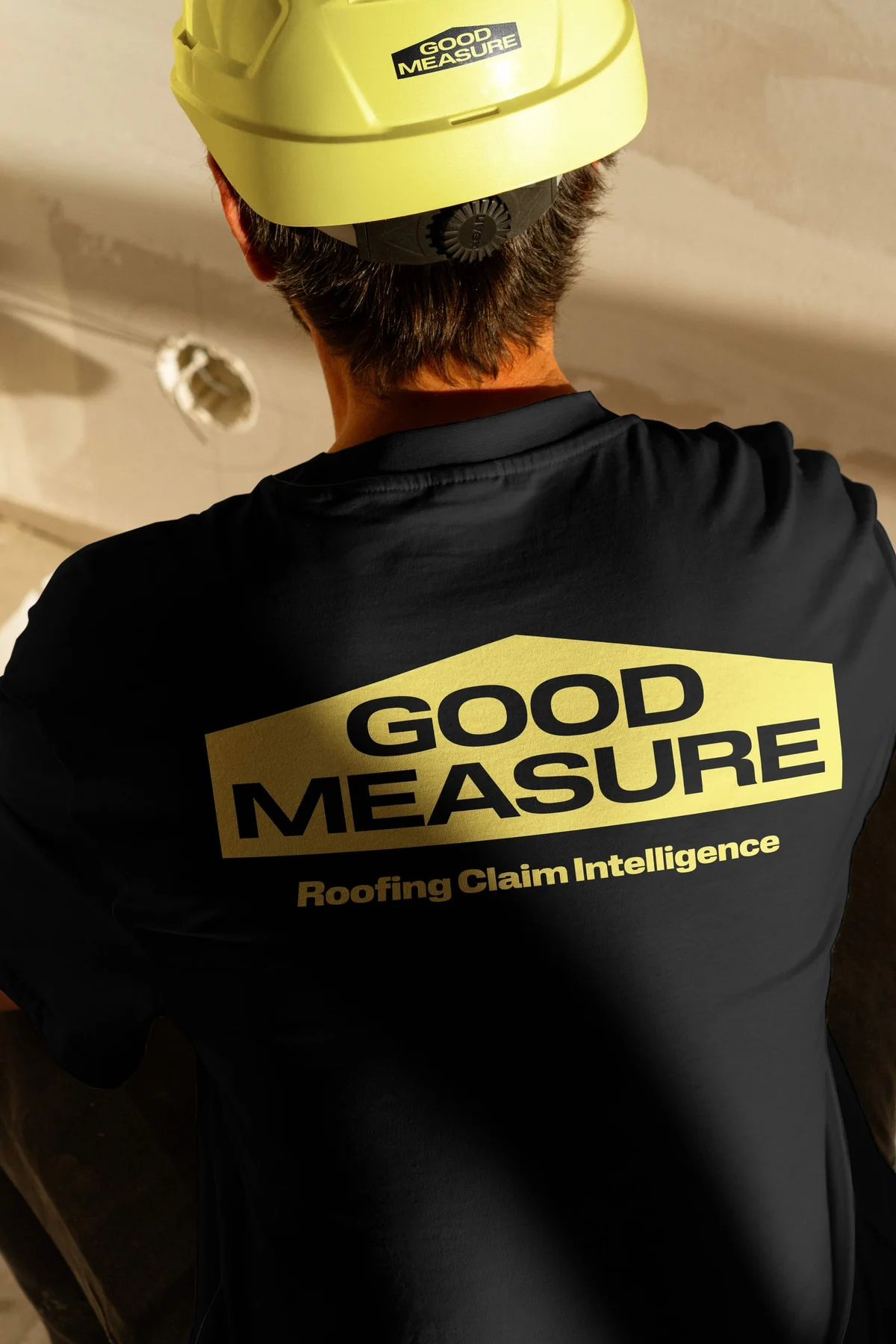 Worker wearing a black Good Measure T-shirt and yellow hard hat.
