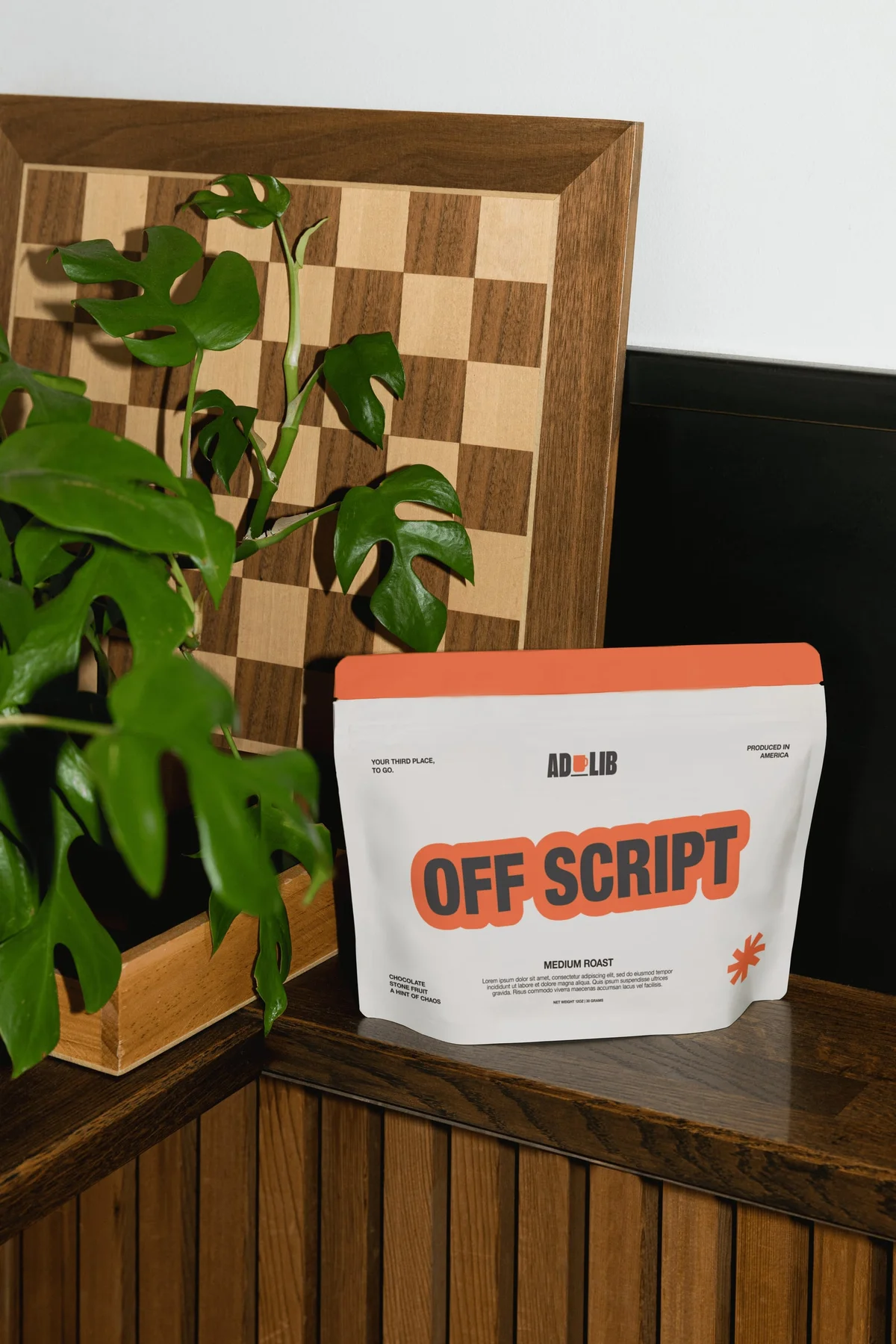 Off Script coffee packaging beside a plant and wooden checkerboard.