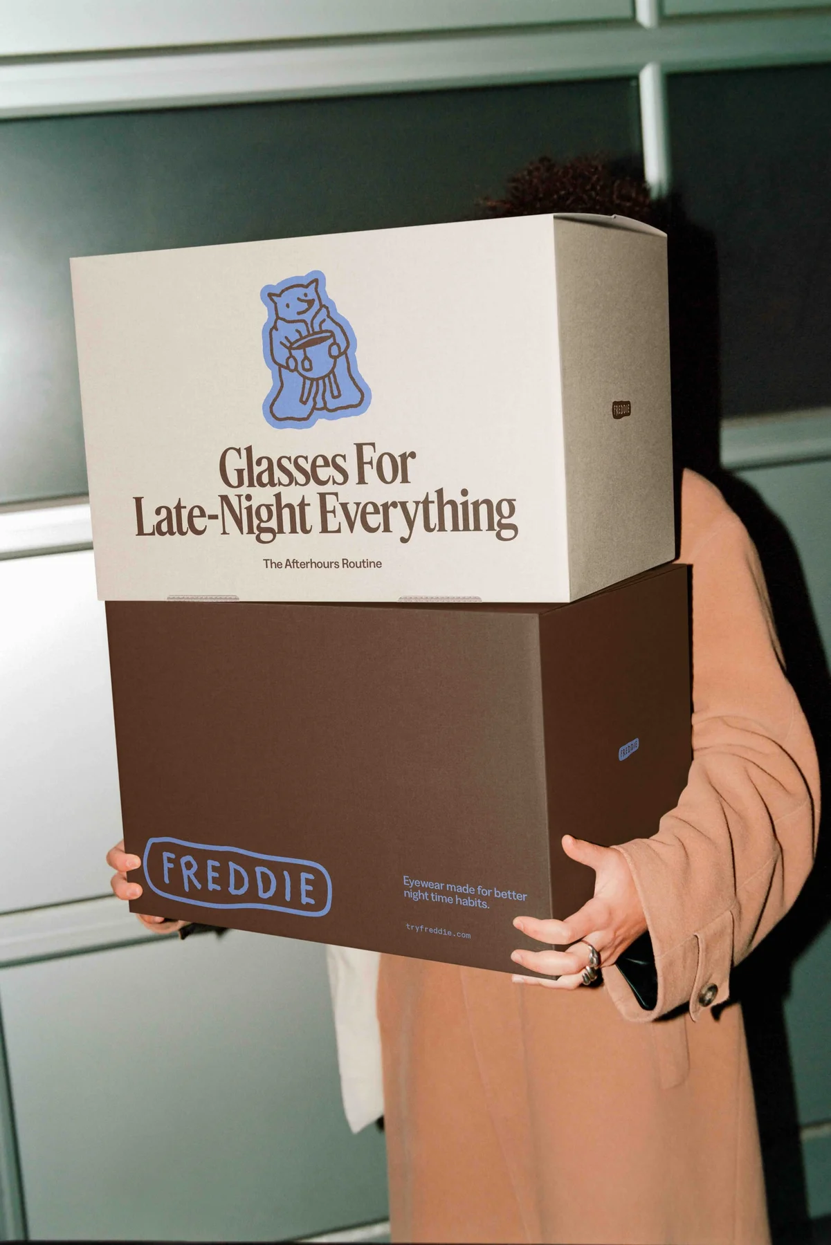 Person carrying a large Freddie box with an illustrated character.