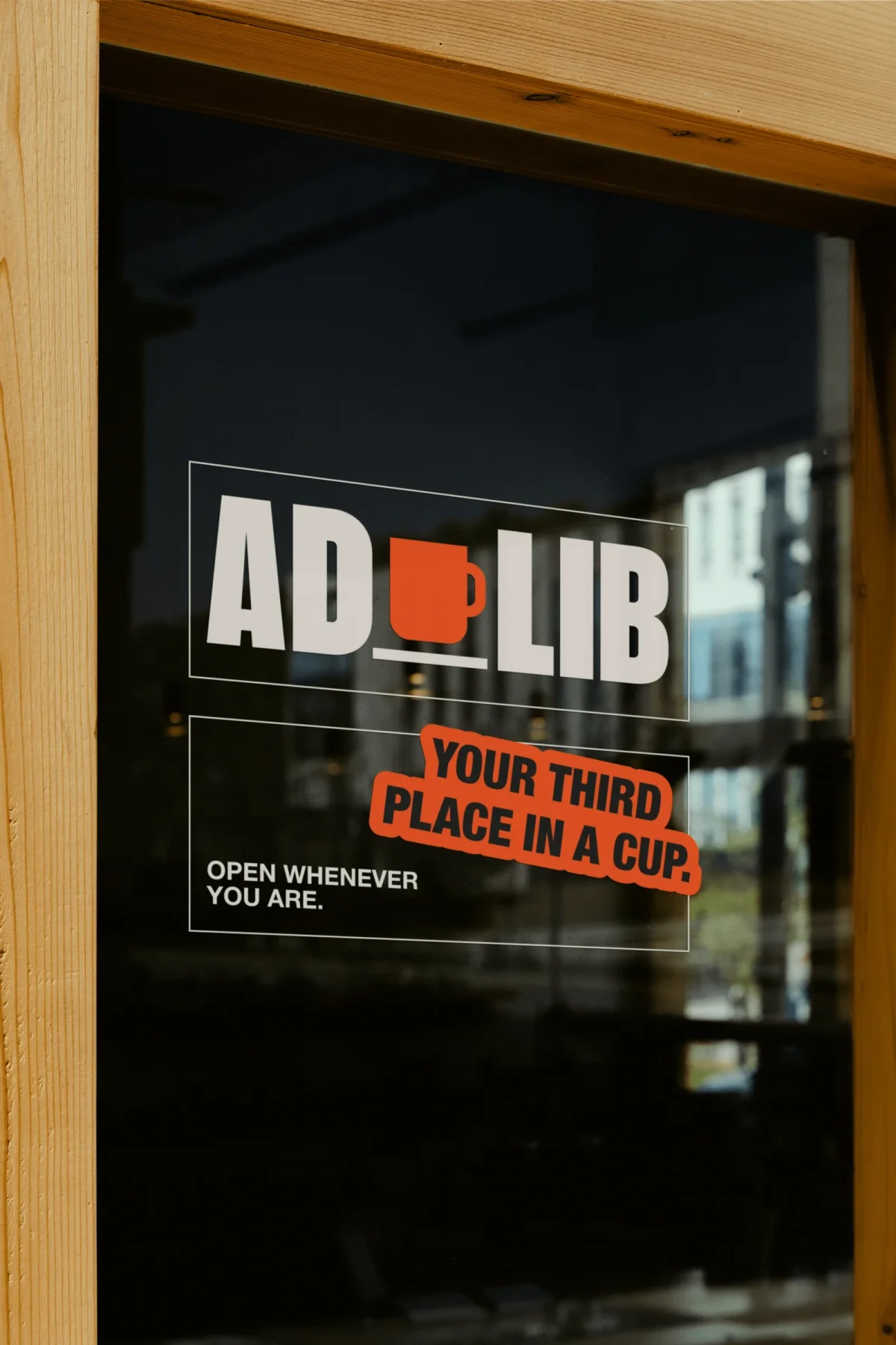 AdLib window lettering with an orange cup and slogan.