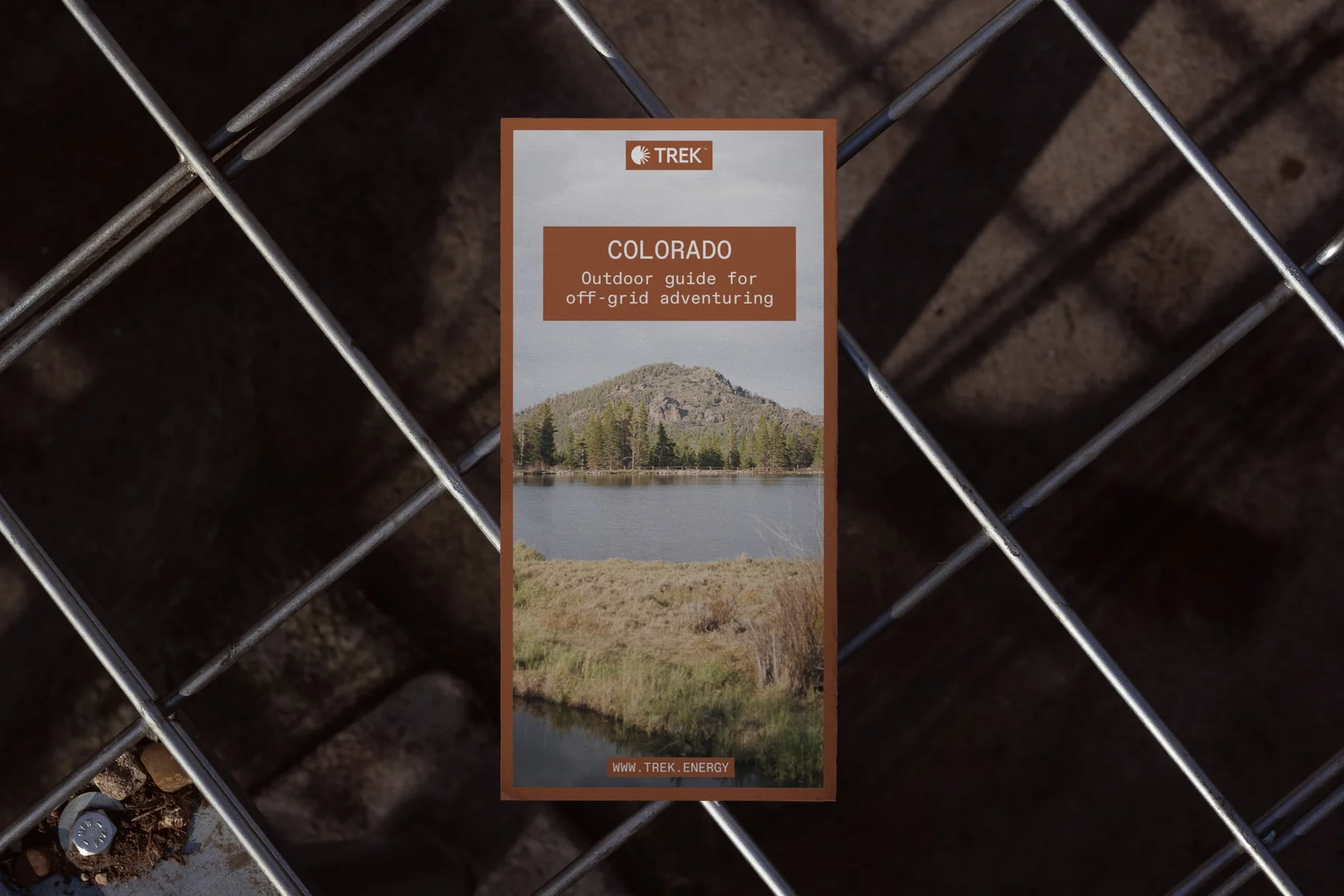 Trek Colorado card with landscape photography on a chain-link fence.