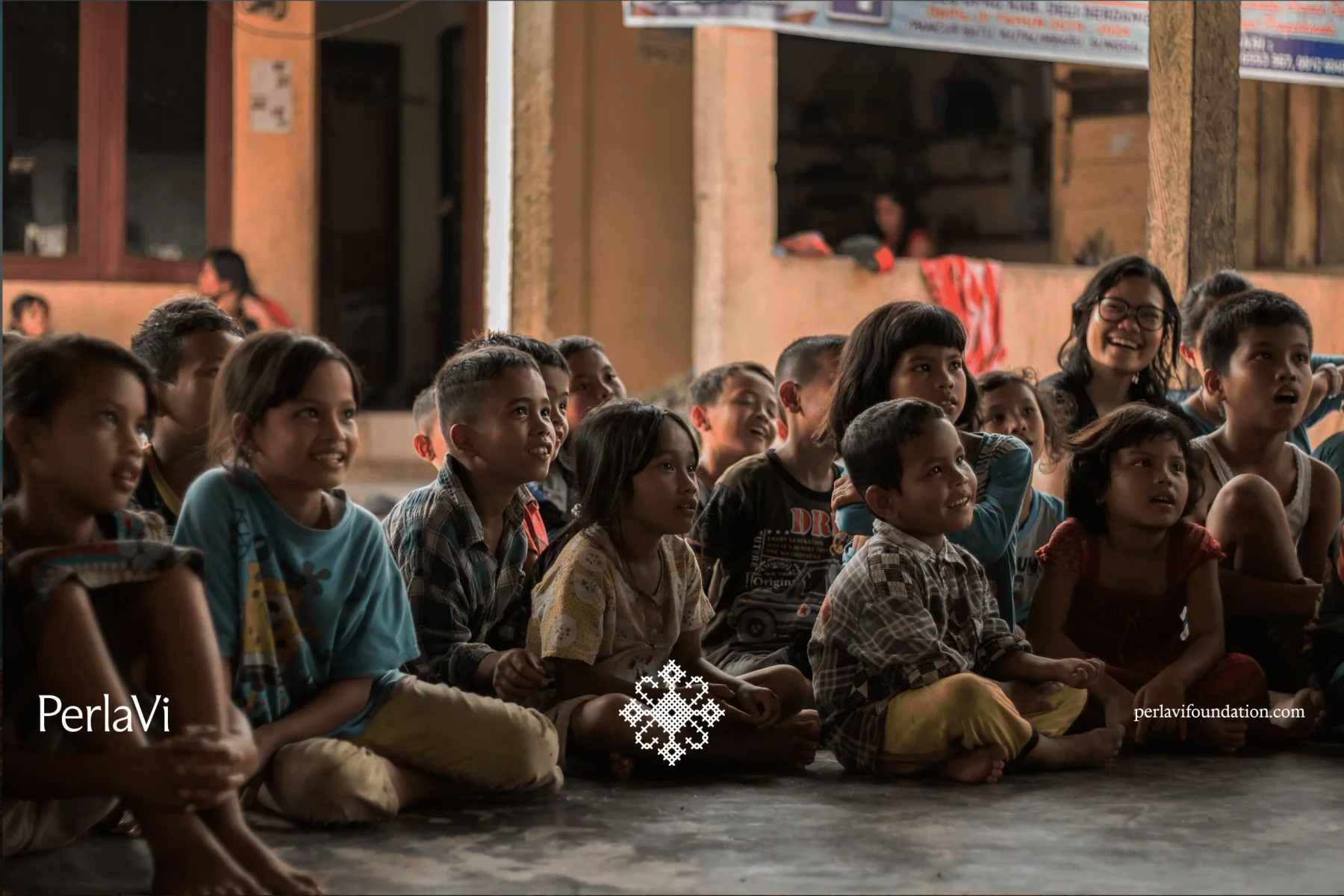 PerlaVi photograph of children seated together, with small white brand marks.
