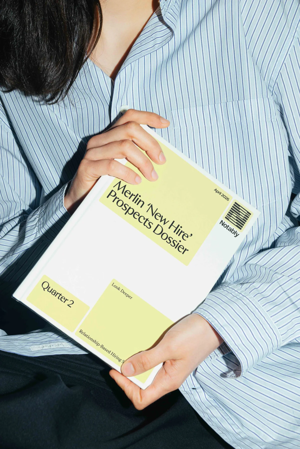 Person holding a Notably publication with pale yellow graphics.