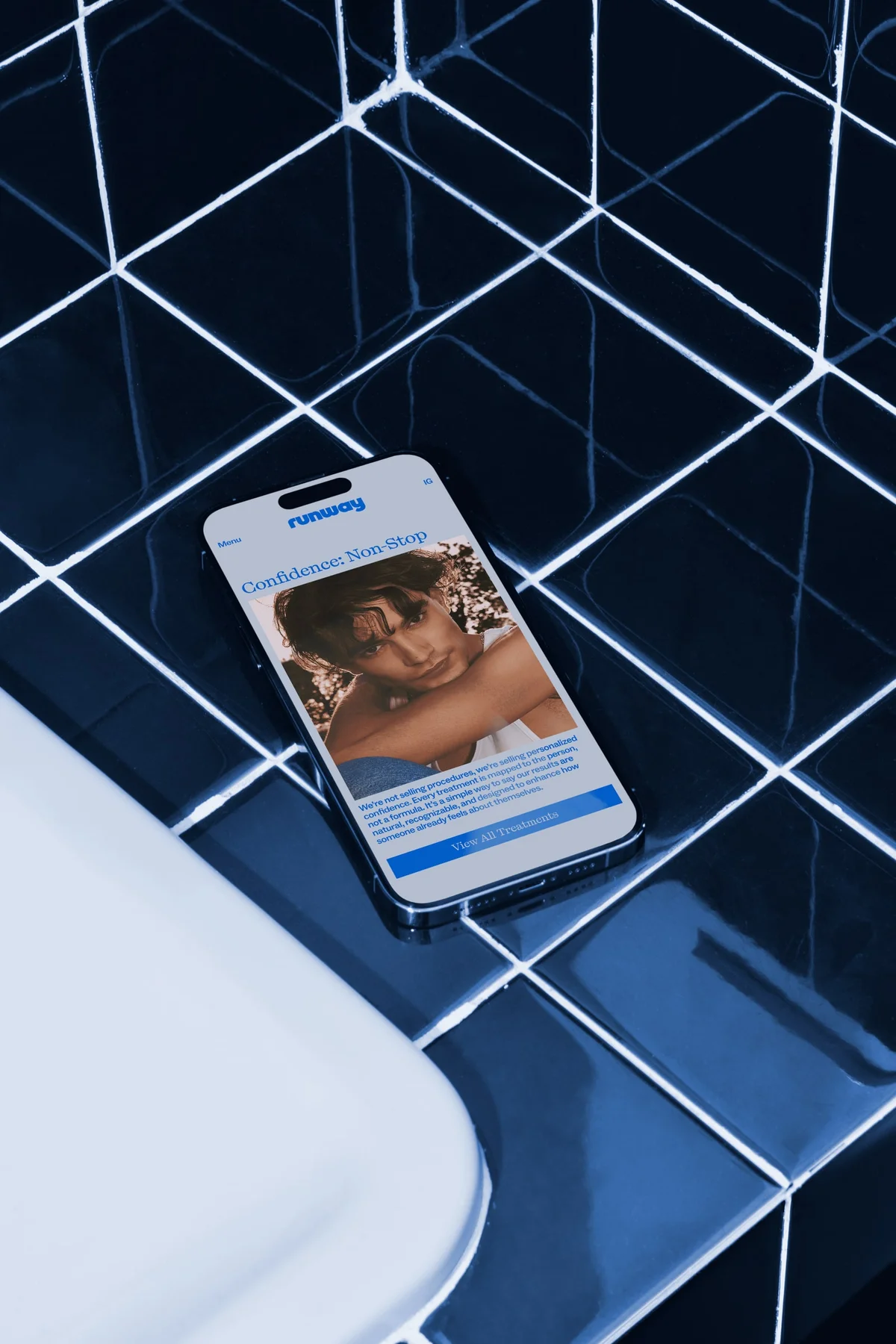 Runway mobile website on a phone against dark blue tiles.
